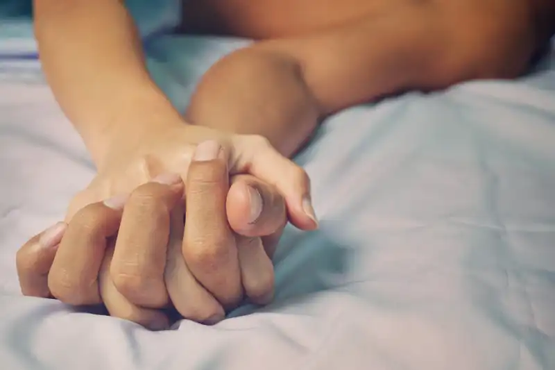 couple holding hands on bed